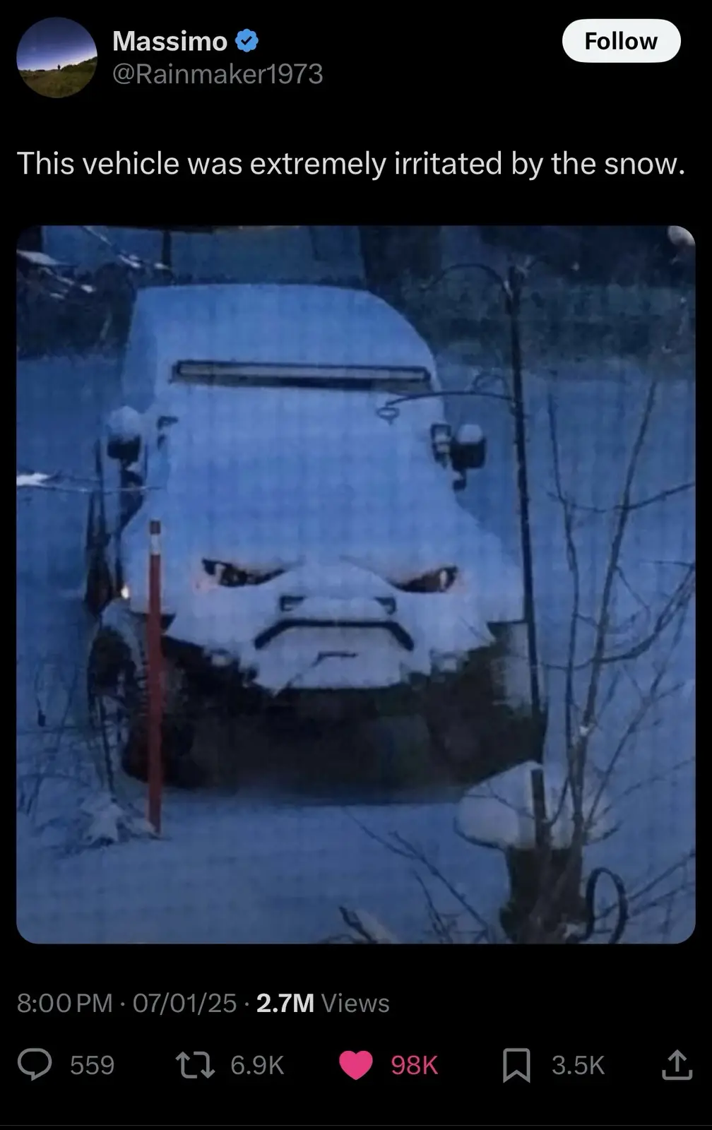 A snow-covered vehicle's front grille and headlights are obscured by snow, creating the illusion of an angry face with…