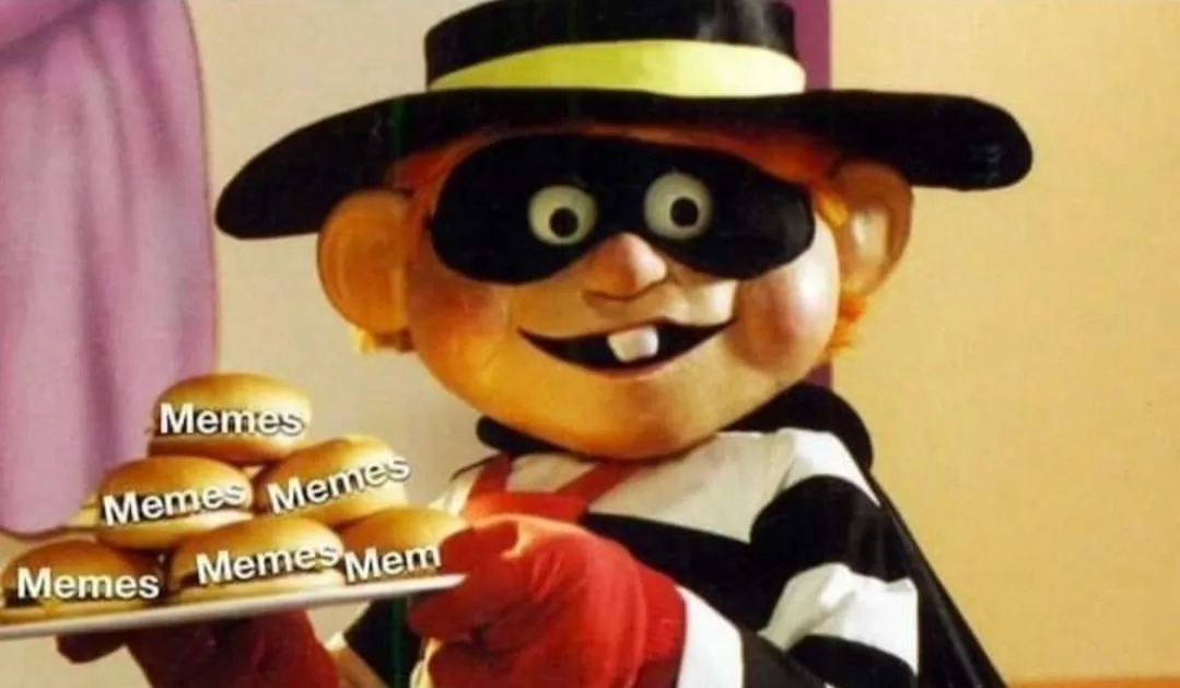A cartoonish puppet character dressed as a thief, wearing a black mask and hat, holds a tray piled with golden-brown buns…
