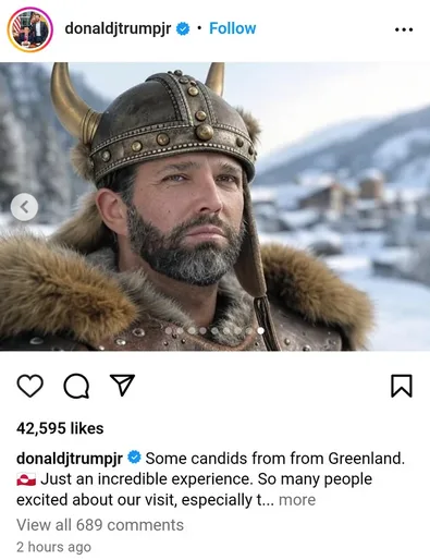 A man with a beard and mustache wears a horned Viking helmet and a fur-lined armor jacket, standing in a snowy landscape…