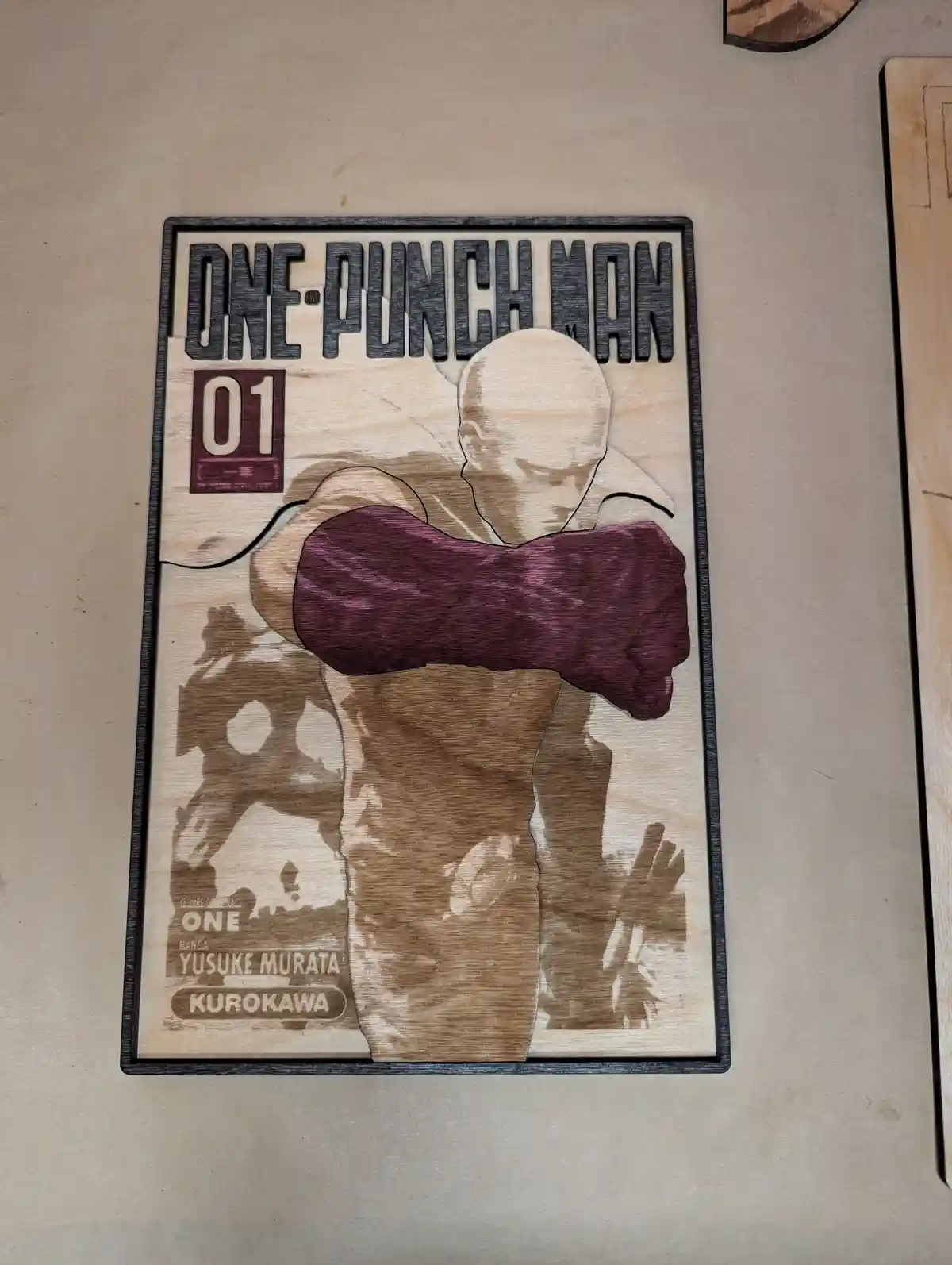 A wooden laser-cut replica of the cover of 'One-Punch Man' volume 01, featuring the main character Saitama in his signature…
