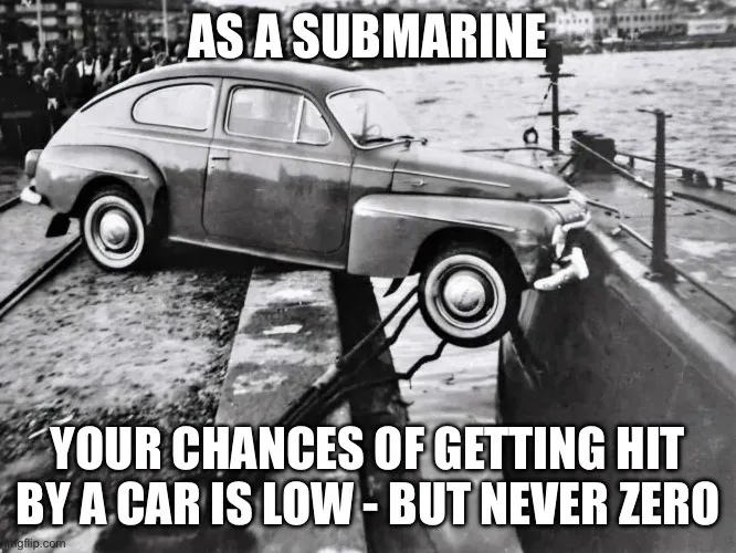 A black and white photo shows a vintage car partially submerged in water, appearing to be on the deck of a submarine. The…