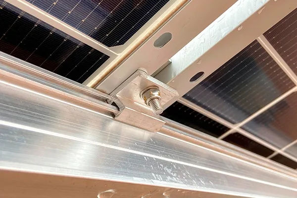 A close-up photo of solar panels mounted on a metal frame, showing a single bolt securing the panels. The overlaid text…