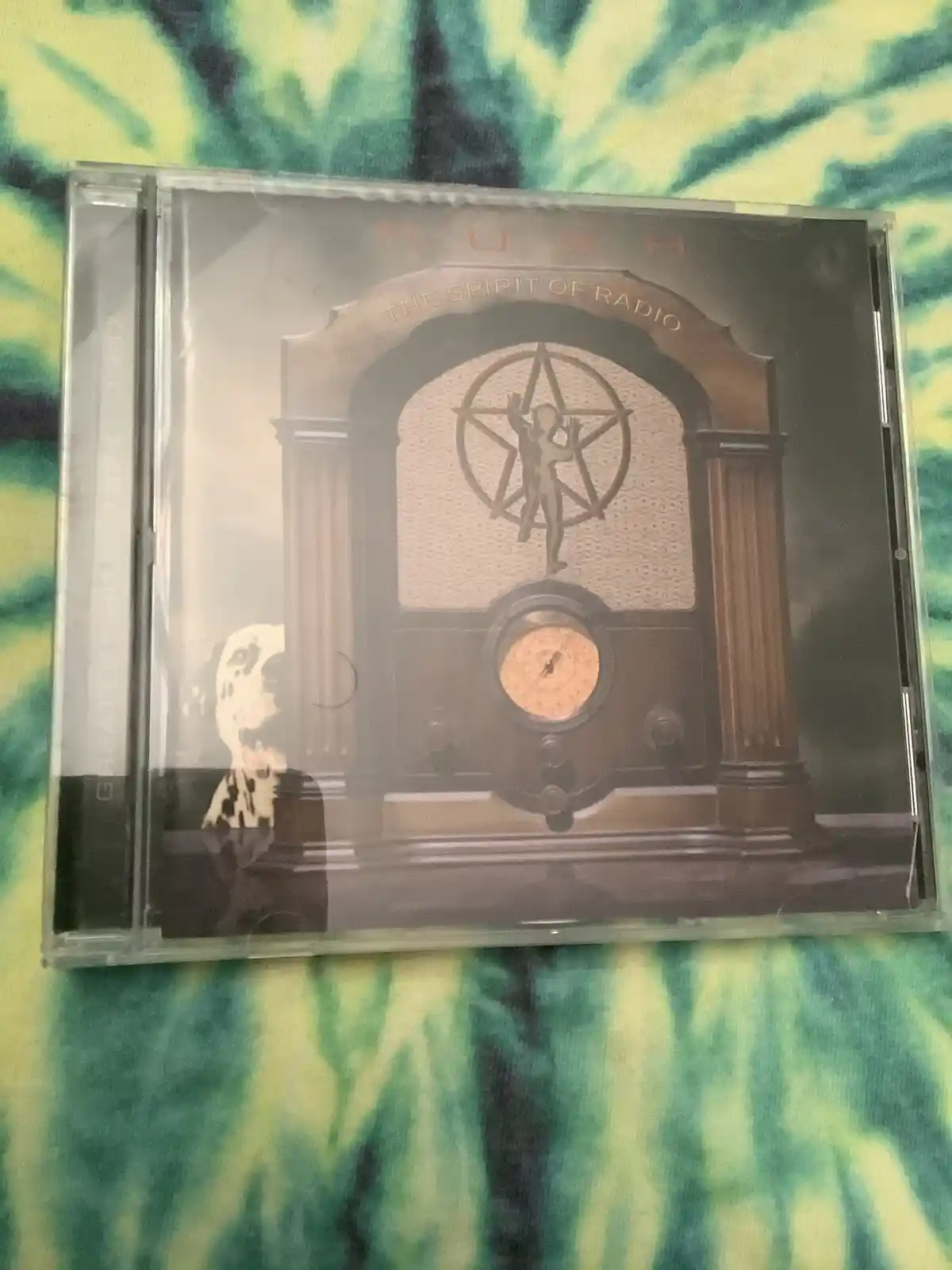 A CD case for Rush's 'The Spirit of Radio' album is shown, featuring an ornate vintage radio with a pentagram and a figure…