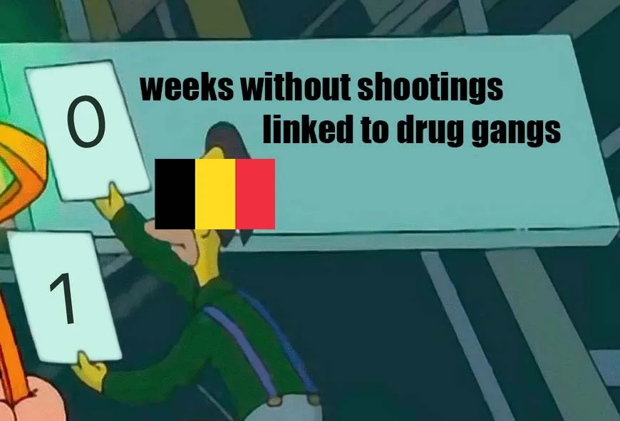 A cartoon character holds up two cards, one with '0' and one with '1', while a sign above reads 'weeks without shootings…