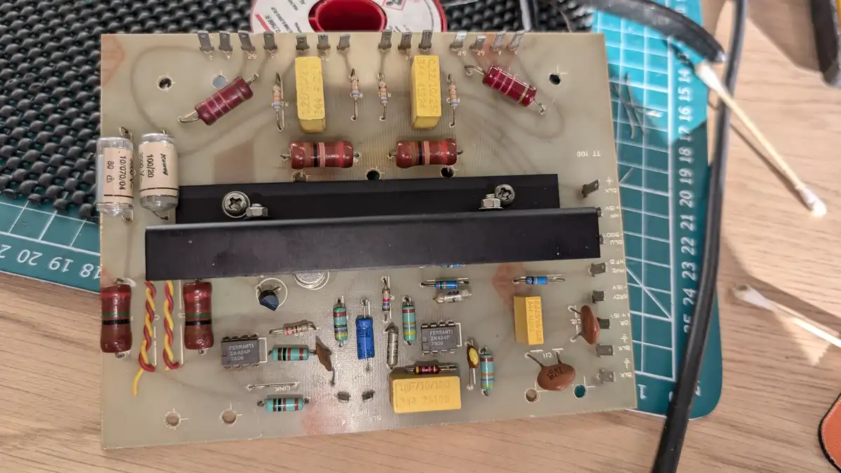 A close-up photo of a beige circuit board with various electronic components like resistors, capacitors, and integrated…