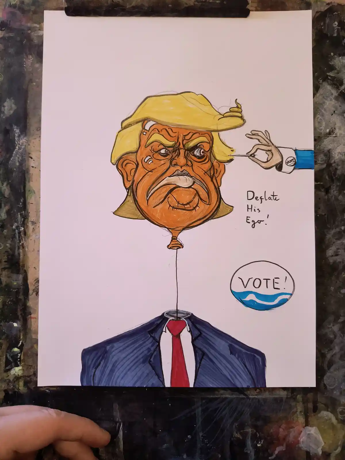 A hand with a 'VOTE' cuff is using a needle to deflate a balloon caricature of Donald Trump, whose head is the balloon and…