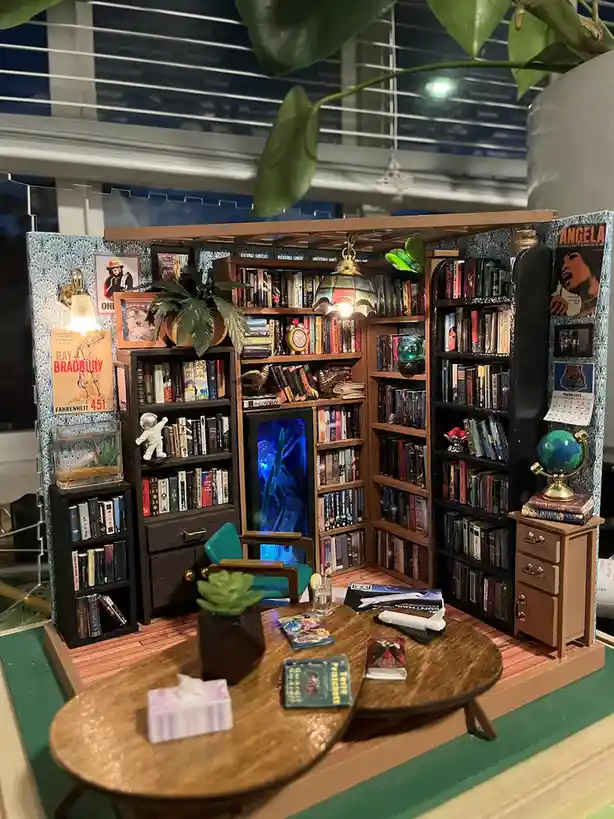 A meticulously crafted miniature diorama of a cozy, book-filled room, complete with tiny bookshelves overflowing with books…