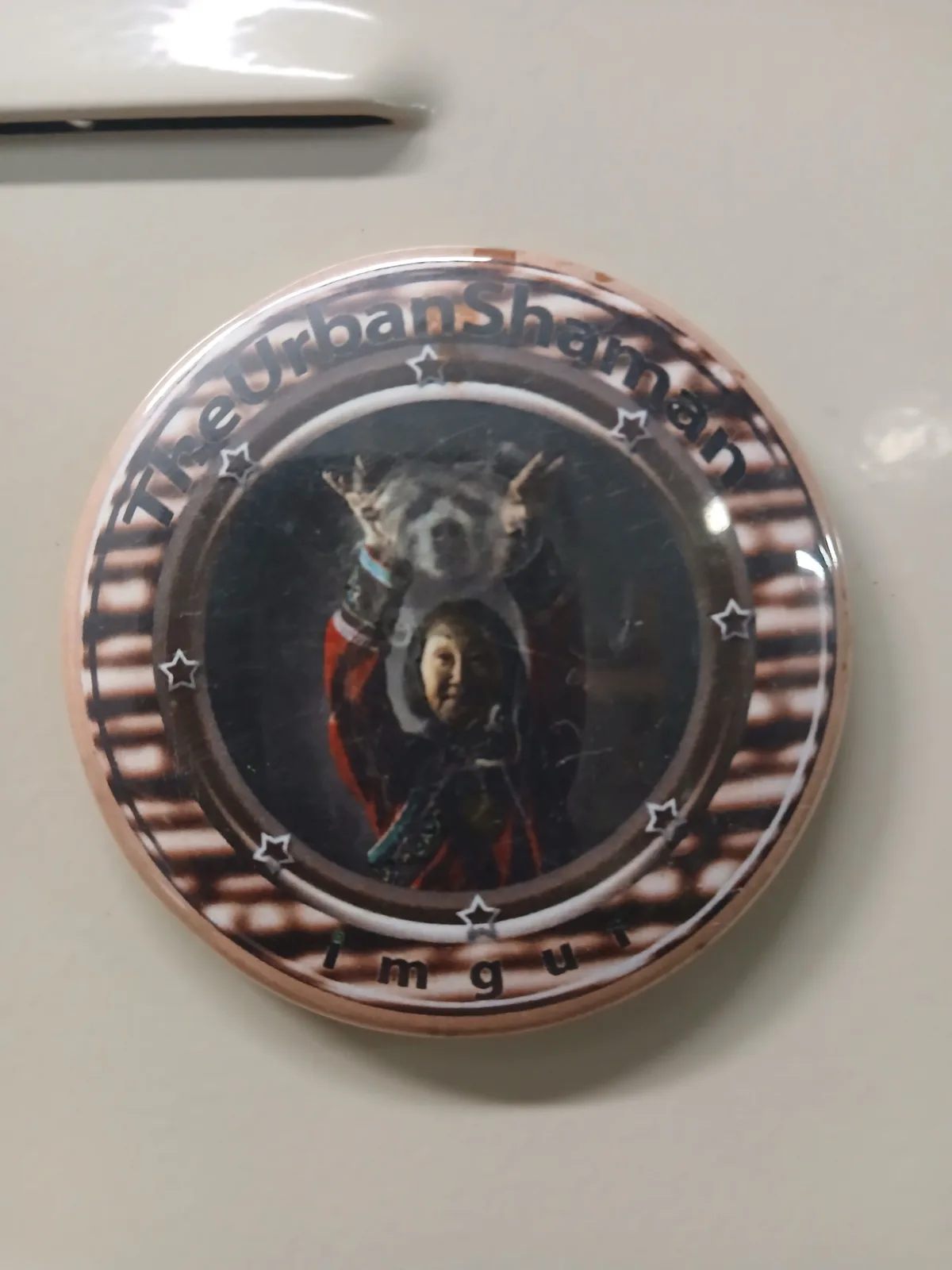 A circular button features a photo of a person in traditional attire holding up a spirit animal, surrounded by stars and…