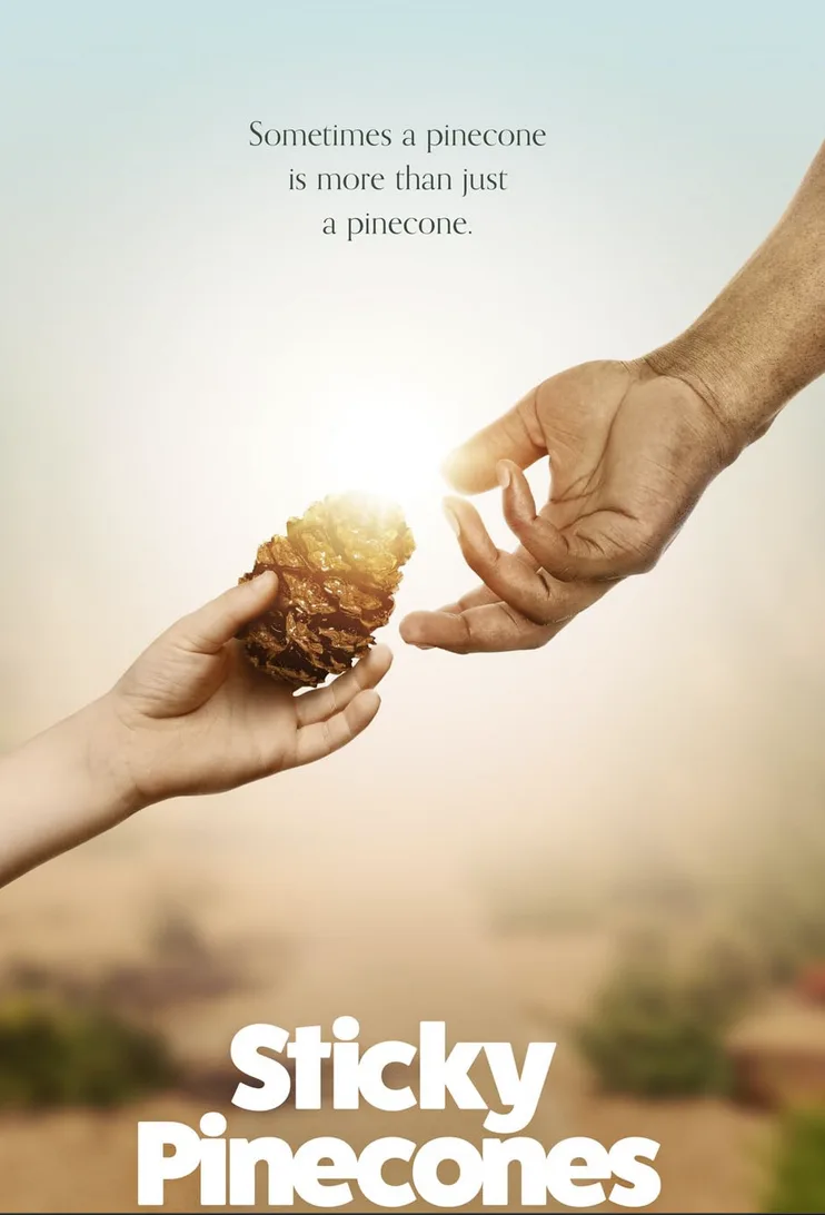 Two hands reach toward each other across a bright, hazy background, one holding a pinecone while the other reaches to touch…