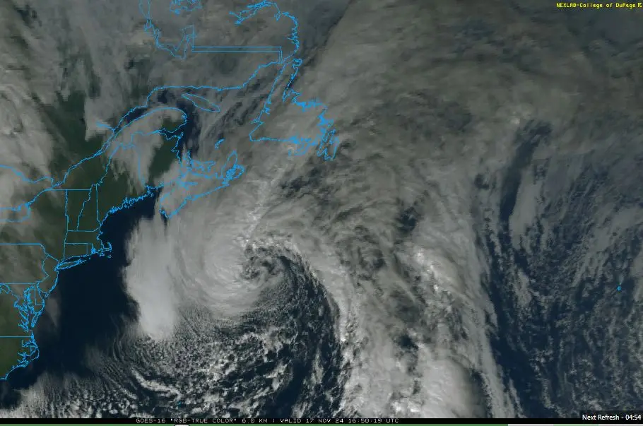 A satellite image shows a large hurricane swirling over the Atlantic Ocean near the eastern coast of North America, with…