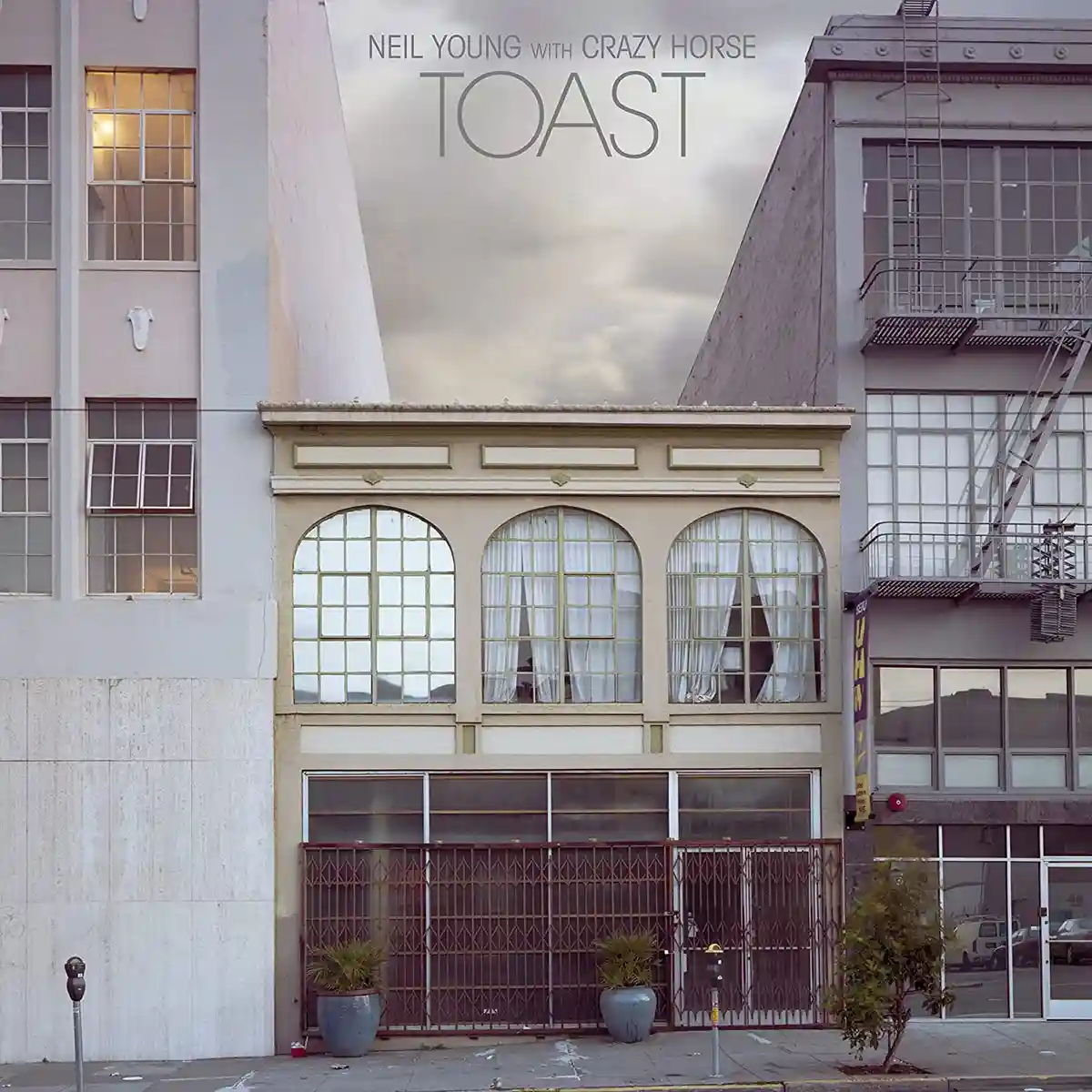 The image shows the album cover for Neil Young with Crazy Horse's 'Toast,' featuring a photograph of a closed storefront…
