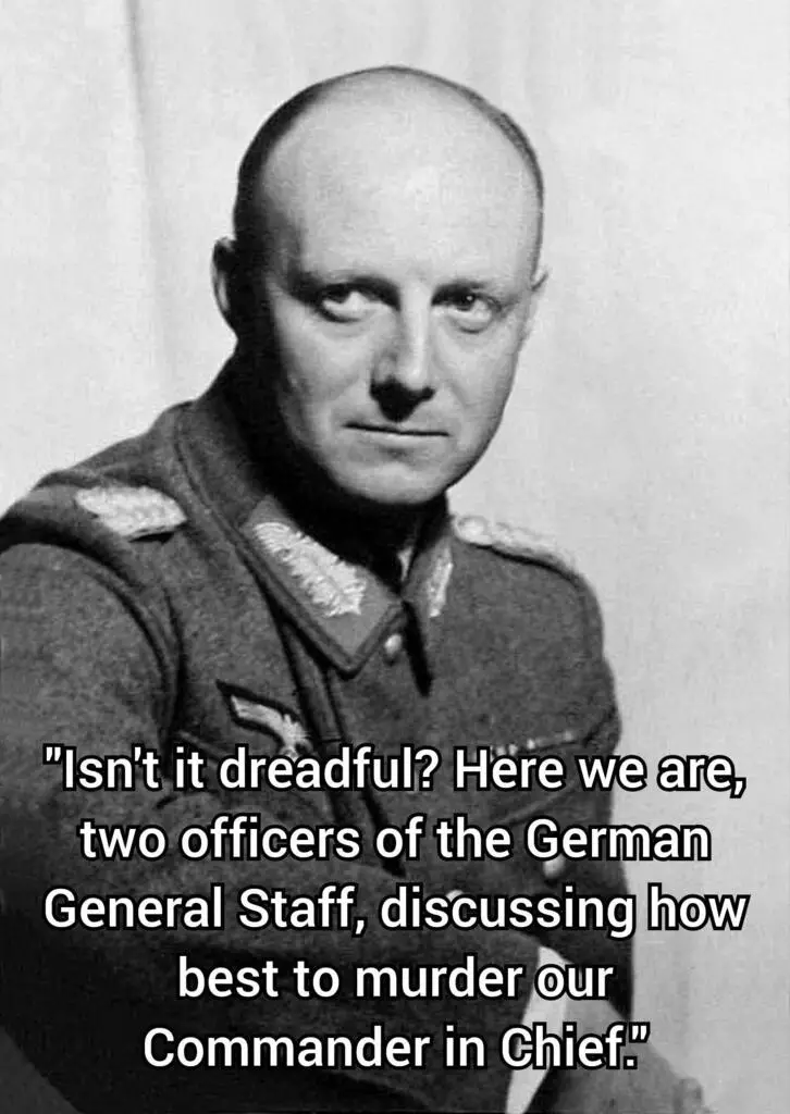 A black-and-white photograph of a balding man in a military uniform with insignia, looking directly at the camera with a…