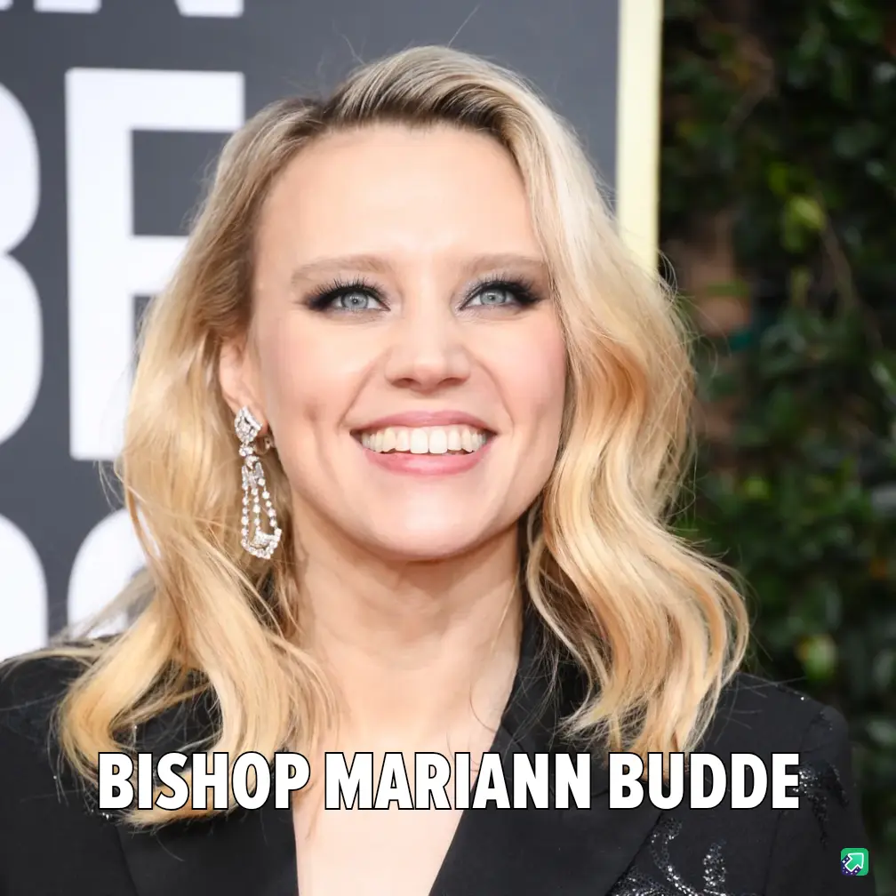 A close-up photo of a smiling blonde woman with blue eyes, wearing a black outfit and dangling diamond earrings, at what…