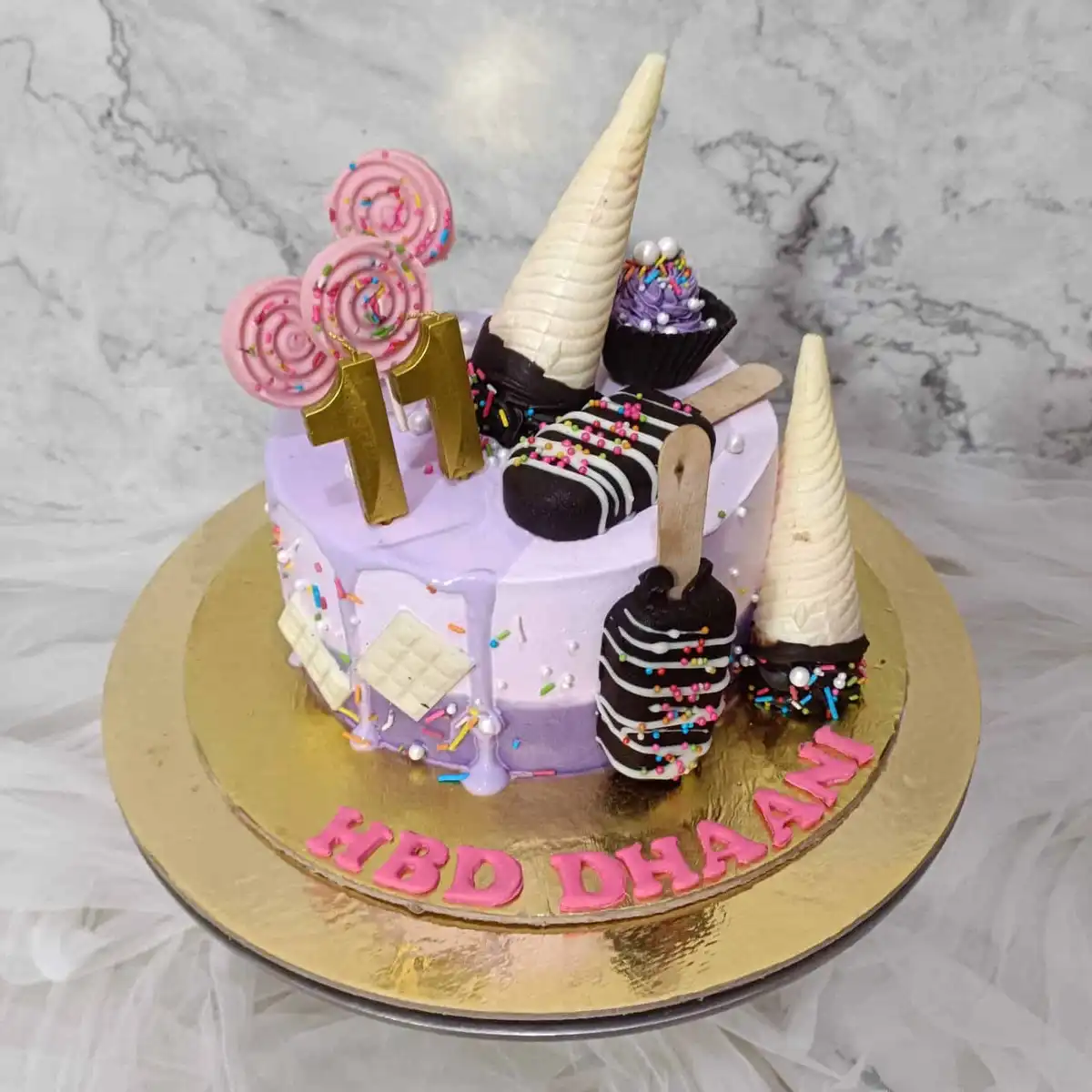 A lavishly decorated purple birthday cake with gold number 11 candles, pink lollipops, chocolate-covered ice cream cones…