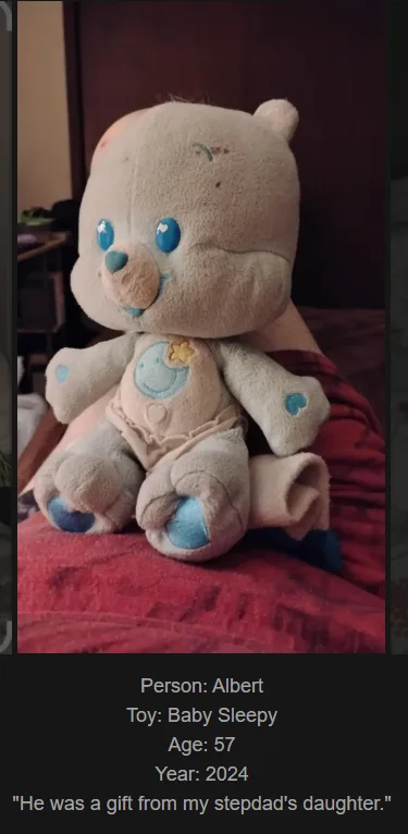 A worn, light-colored plush teddy bear with blue eyes and blue paw pads sits on a red fabric surface. Text overlaid at the…