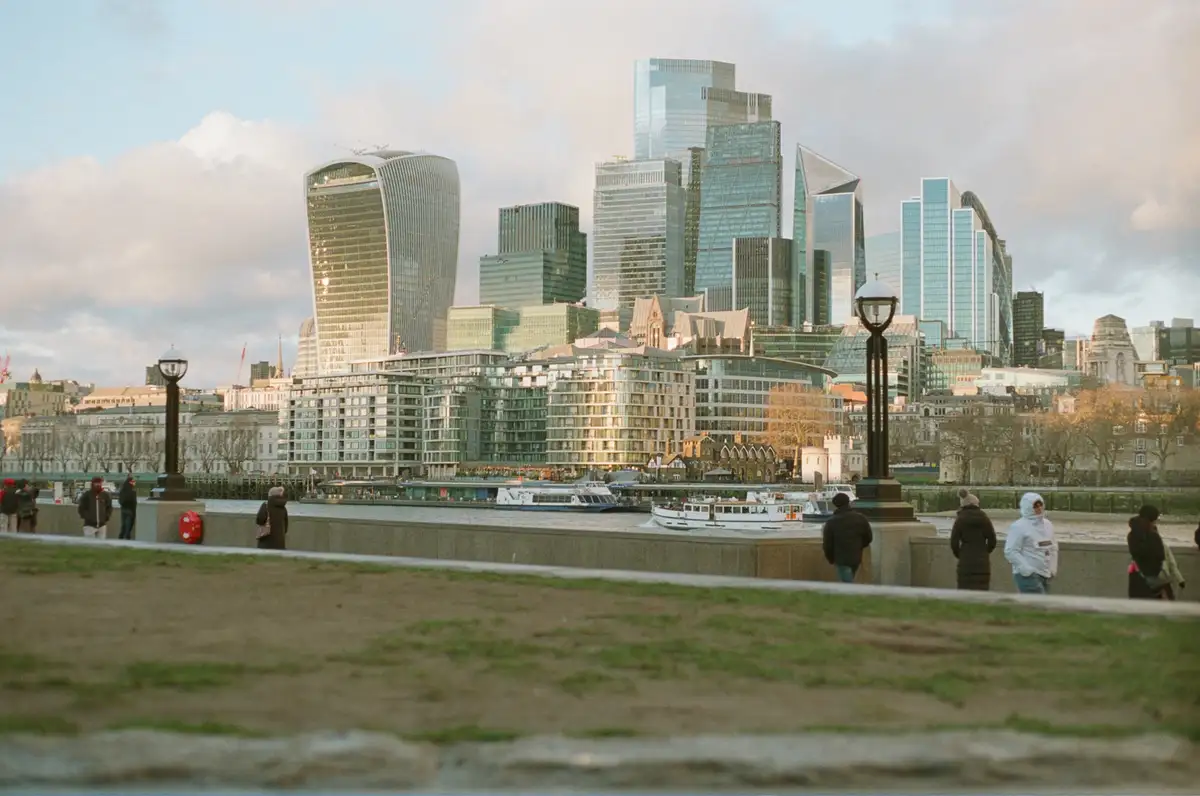 A scenic photo of London's skyline along the Thames River, featuring modern glass skyscrapers like the Gherkin and…
