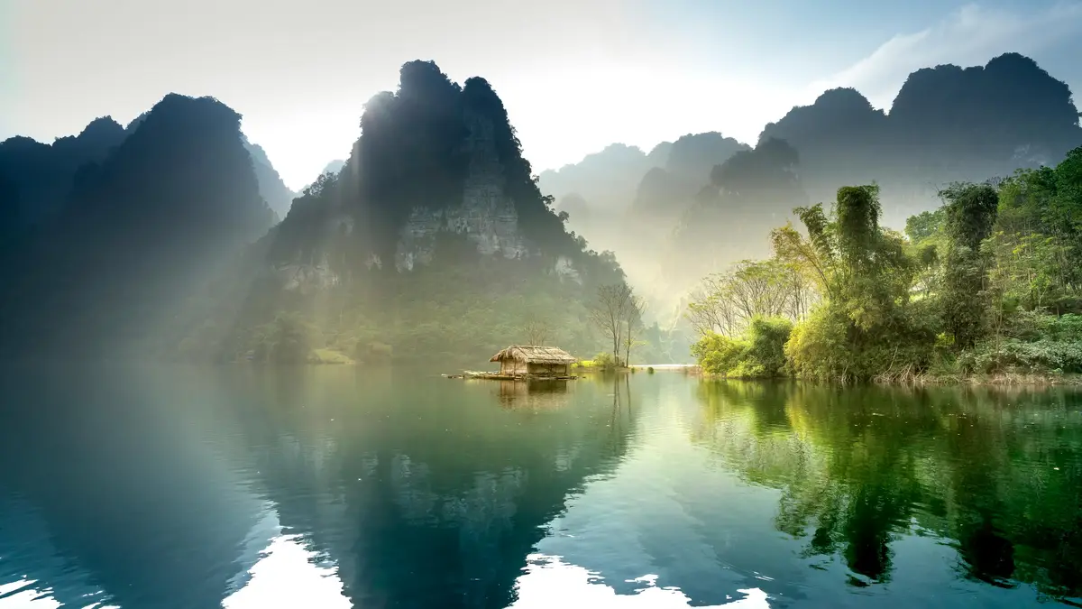Golden light creeps over the still lake, casting a warm glow on the misty mountains. Reflections ripple, a kaleidoscope of…