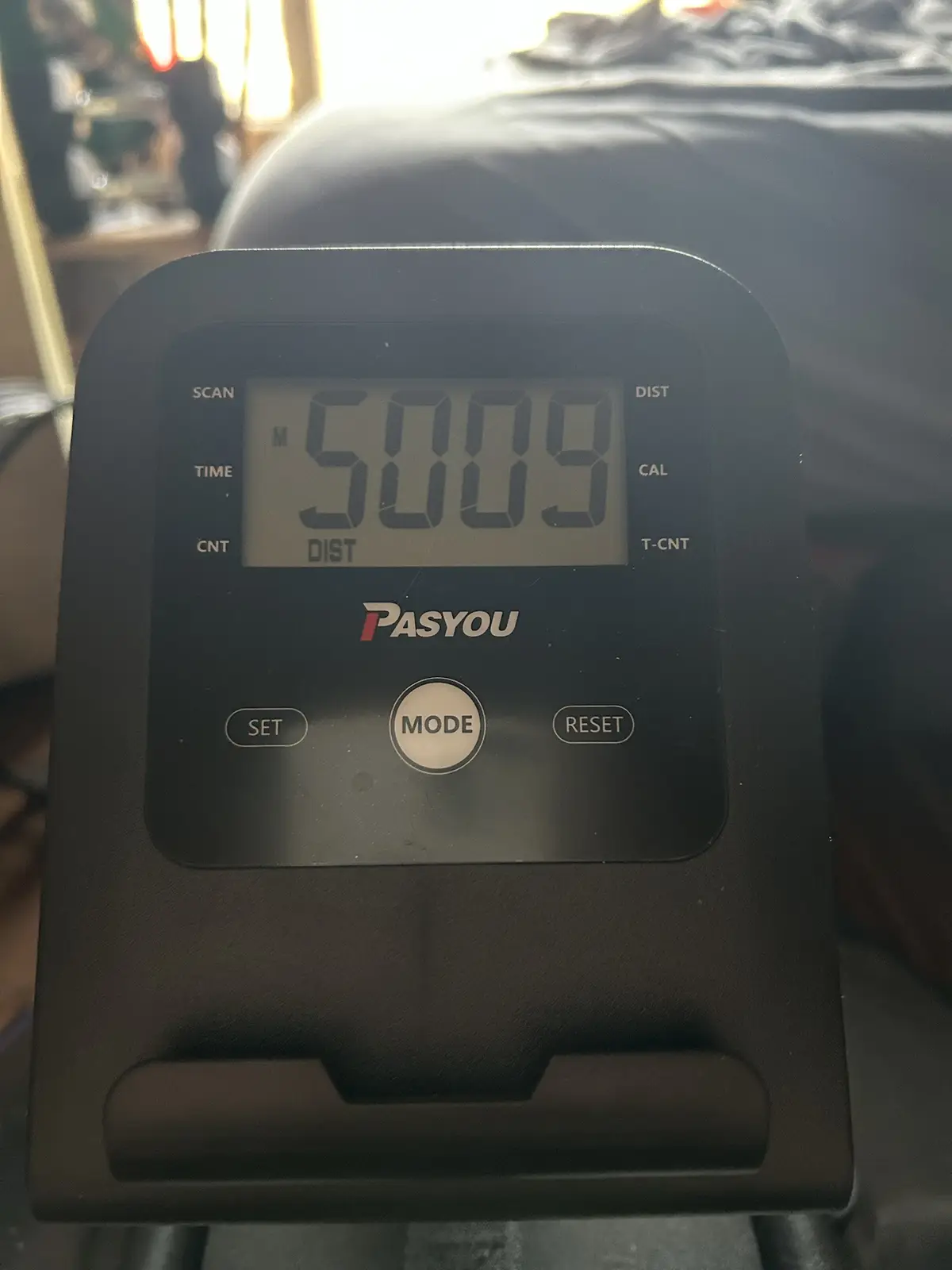 A close-up of a black PASYOU treadmill console displaying the number 5009 under the 'DIST' (distance) label, with buttons…