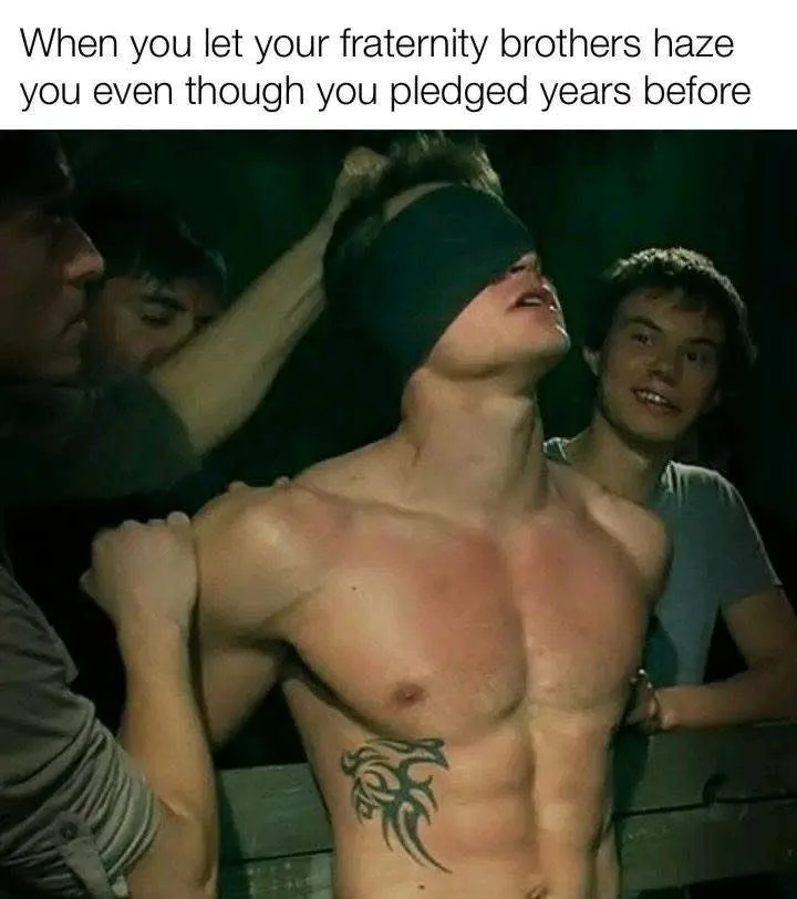 A shirtless man with a tribal tattoo on his abdomen is blindfolded and being held by several other men in a dark setting…