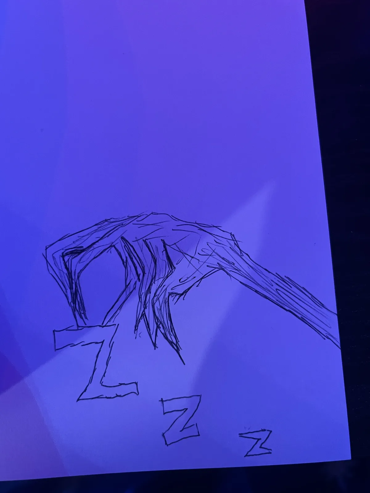 A hand-drawn sketch on paper shows a stylized, messy-haired head with a large 'Z' drawn beneath it, and two smaller 'Z's…
