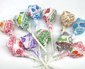 A pile of colorful Dum Dums lollipops with various fruit-flavored wrappers, arranged on a white background. The text 'dum…