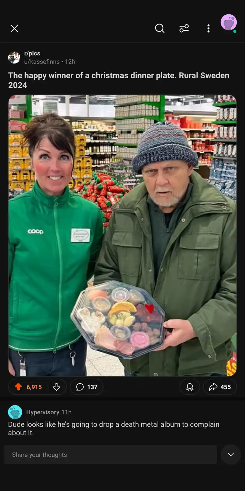 A woman in a green 'coop' jacket stands beside a man in a green jacket and knit hat, both in a supermarket aisle. The man…