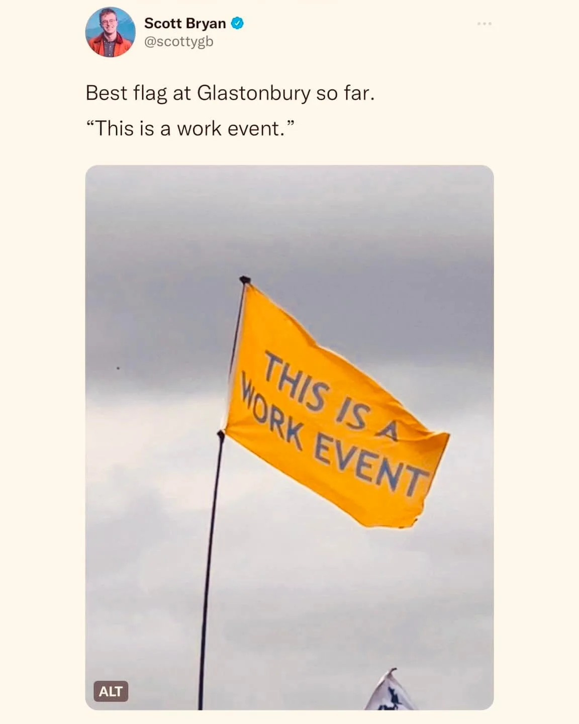 A bright yellow flag on a pole flaps in the wind against a cloudy sky, displaying the text 'THIS IS A WORK EVENT' in bold…