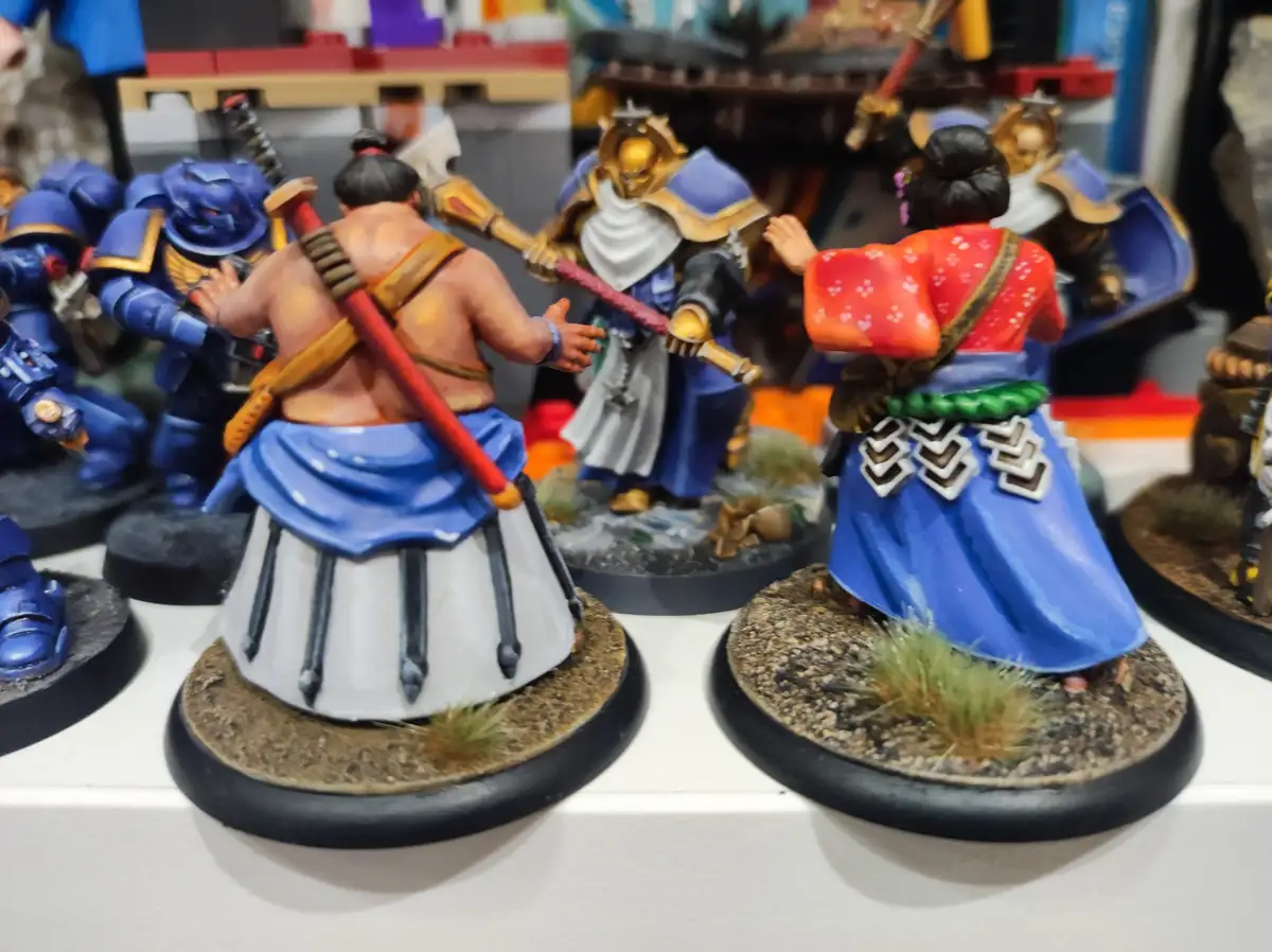 A photo of several painted miniature figurines, including two samurai-style figures in traditional Japanese attire facing…