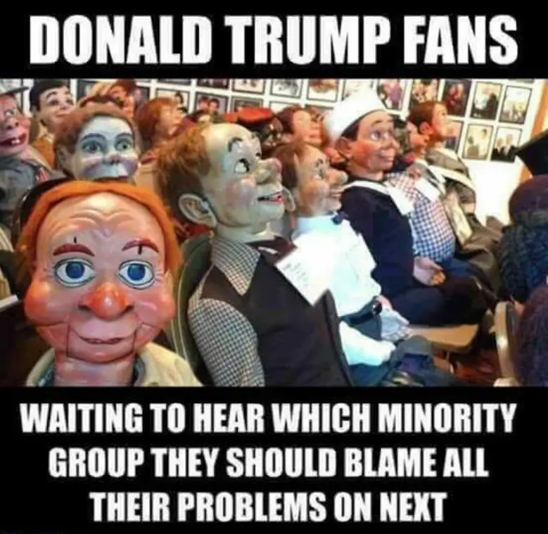 An image shows a crowd of people wearing grotesque, exaggerated, racist-looking masks resembling caricatures of various…