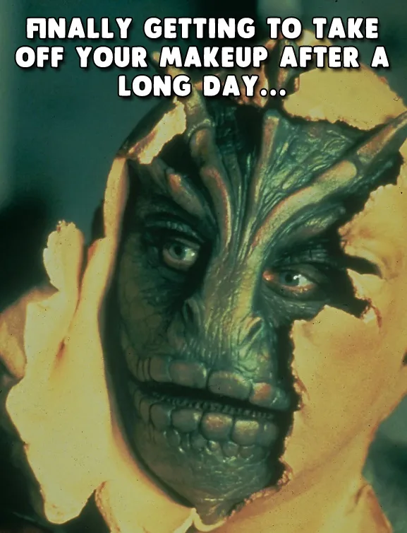 A close-up image shows a person with a green, textured alien-like mask being peeled off their face, revealing human skin…