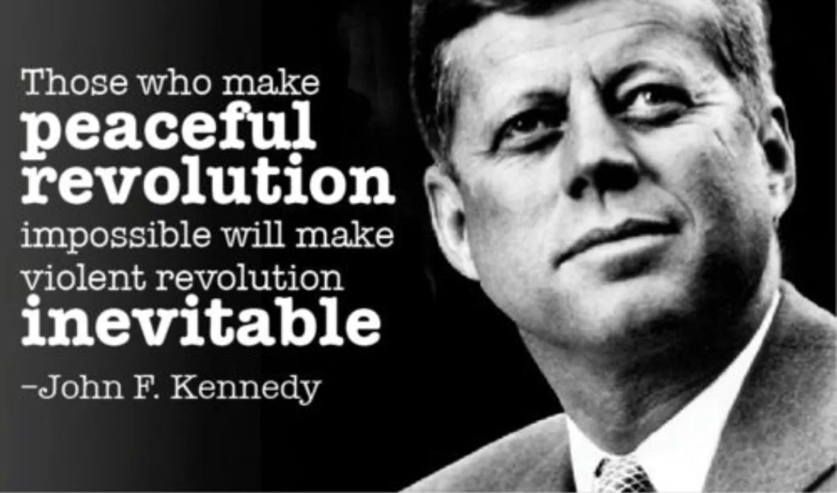 A black-and-white photo of John F. Kennedy looking upward and to the side, with white text overlaid on the left side of the…