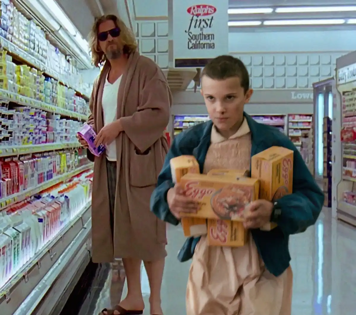 In a brightly lit grocery store aisle, a young boy with a serious expression holds multiple boxes of Eggo waffles, while a…