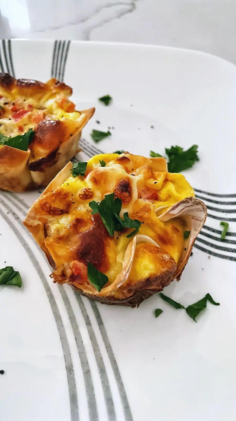 Two baked egg and cheese cups in a white plate with grey stripes, garnished with parsley. The text overlay reads 'i made…