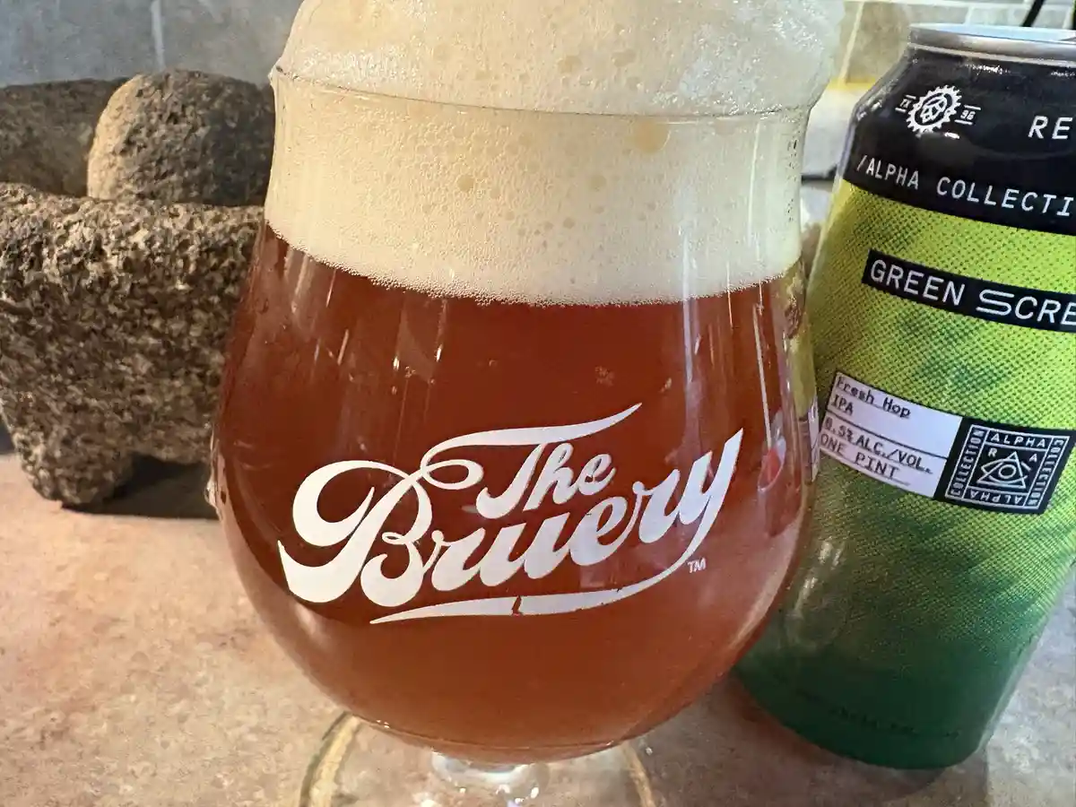 A close-up photo shows a glass of amber-colored beer with a thick white head, branded with 'The Bruery' in white cursive…