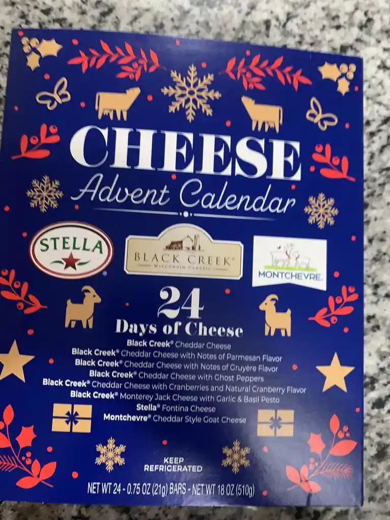 A blue cheese advent calendar box with festive red and gold holiday decorations like snowflakes, holly, and goats. The box…
