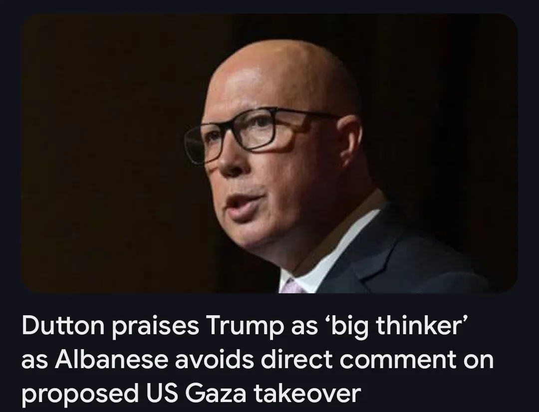 A close-up photo of a bald man wearing black-rimmed glasses and a dark suit, looking slightly to his right with his mouth…