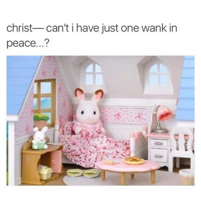 A plush white rabbit doll wearing a pink floral dress sits on a matching sofa in a miniature dollhouse bedroom. The room has…