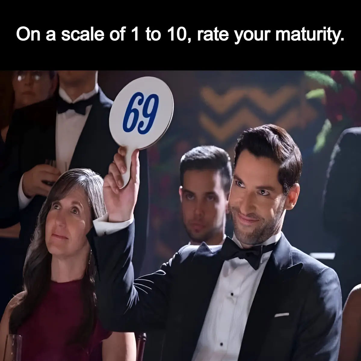 A man in a tuxedo holds up a paddle with the number 69 on it at what appears to be a formal event, while the overlaid text…