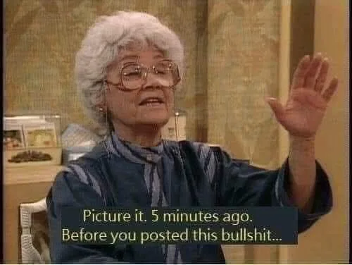 An elderly woman with white hair and glasses, wearing a blue patterned shirt, raises her right hand in a gesture of…