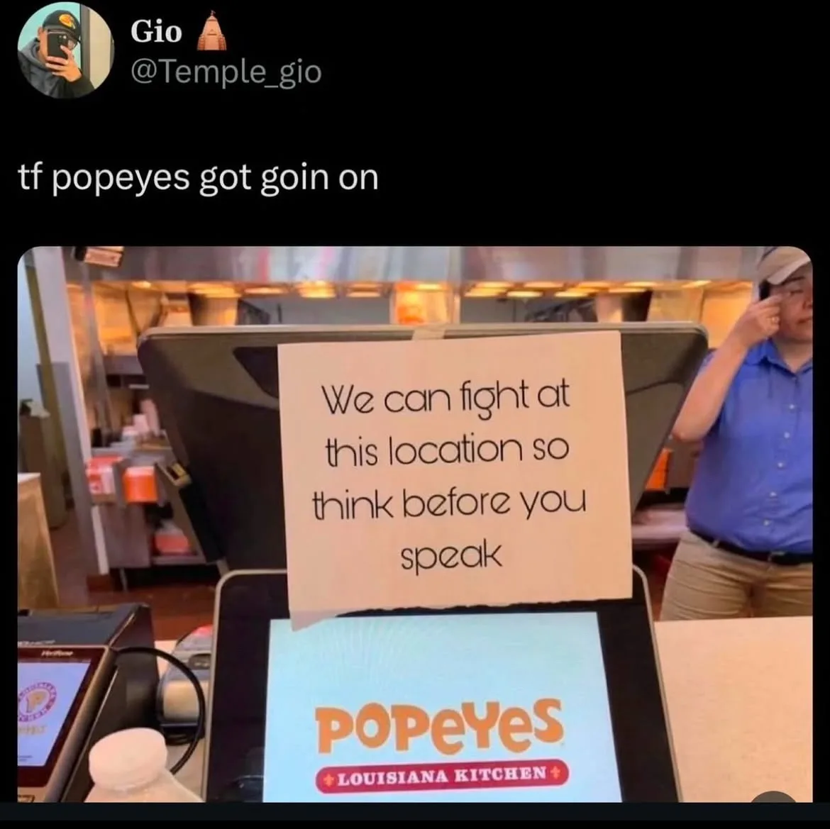 A photo from inside a Popeyes Louisiana Kitchen shows a handwritten sign taped to a register that reads 'We can fight at…