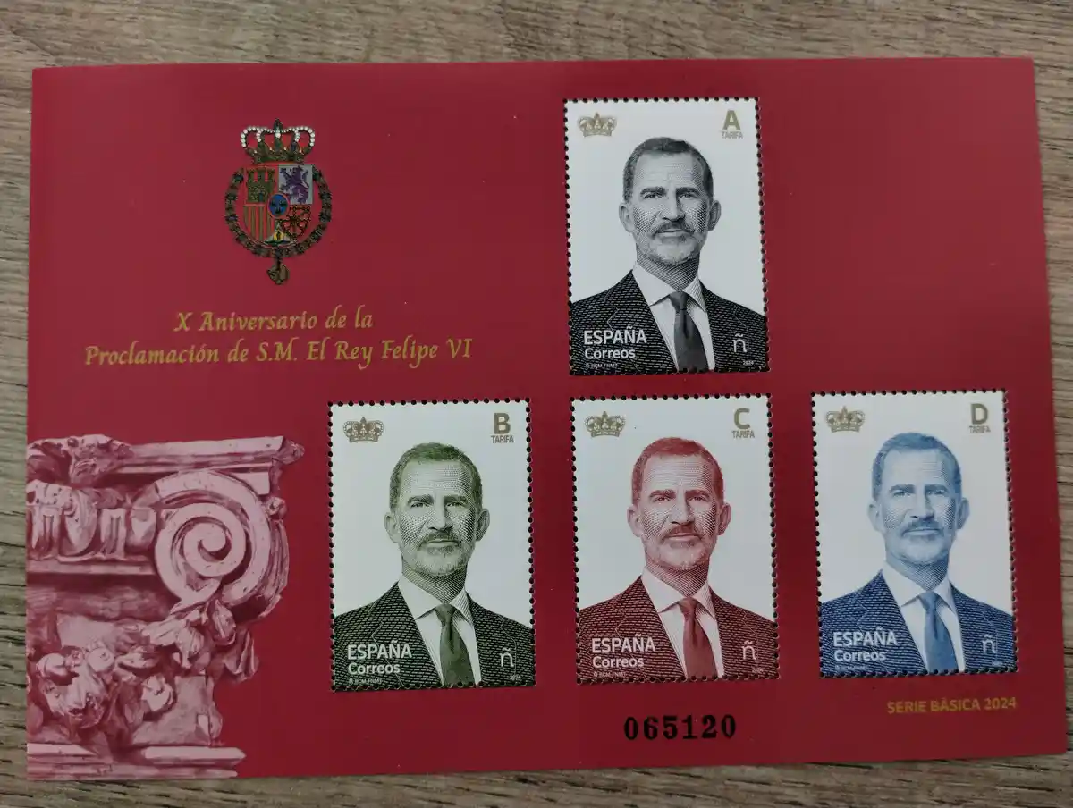 A red Spanish postage stamp booklet commemorating the 10th anniversary of King Felipe VI's coronation, featuring four…