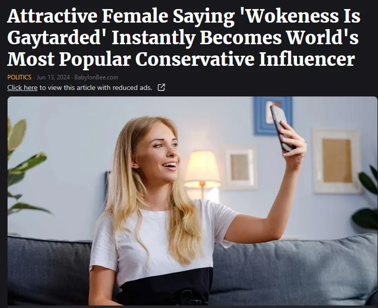 A blonde woman in a white and black top sits on a gray couch, smiling while holding up a smartphone to take a selfie. The…
