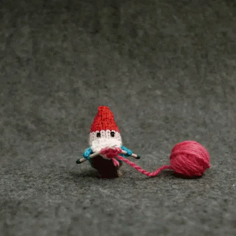 A small knitted gnome with a red hat and white beard is shown in six panels, knitting pink yarn into a heart shape. In the…