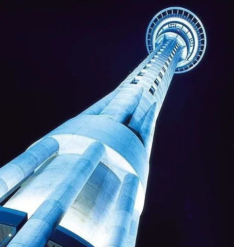 A low-angle nighttime photo of a tall, illuminated observation tower against a dark sky, with overlaid text reading 'i'm not…