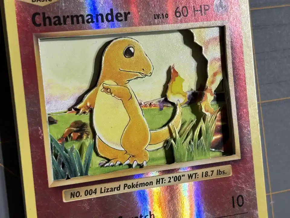 A close-up of a Pokémon trading card featuring Charmander, where the artwork has been physically torn or cut out, revealing…