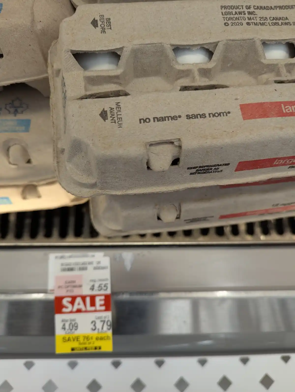 A close-up photo of a generic 'no name® sans nom®' brand egg carton on a supermarket shelf, with a sale price tag below…