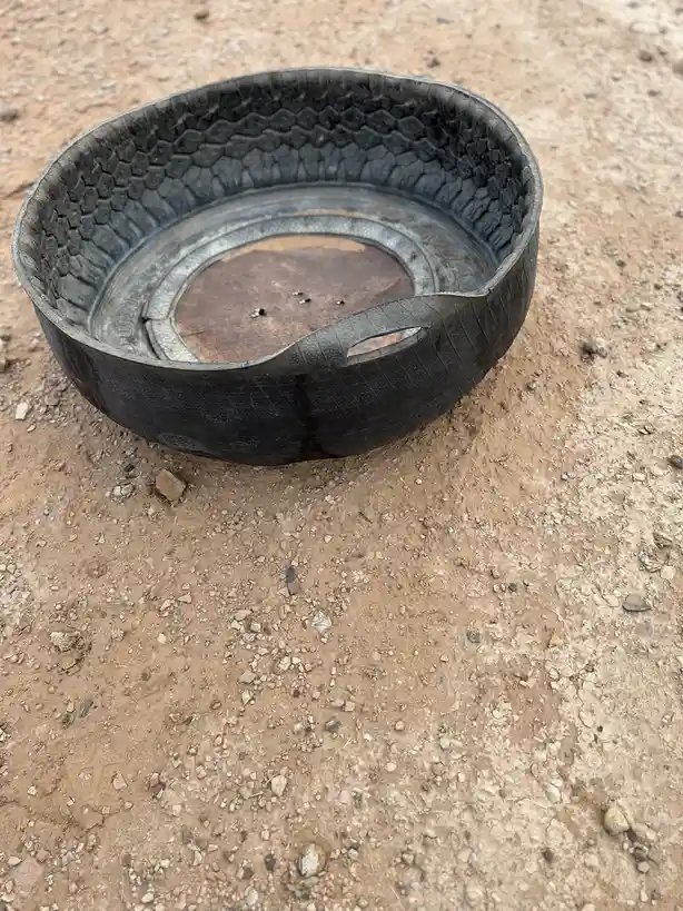 A worn, cut-open car tire sits on a dirt ground, repurposed as a makeshift bowl. The overlaid text reads 'i'm not lazy, i'm…