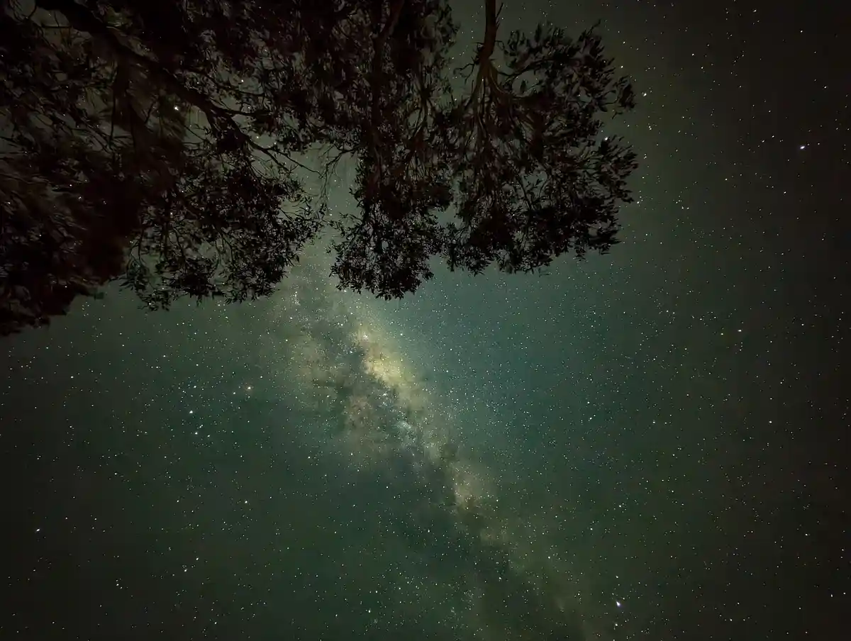 A night sky photograph shows the Milky Way galaxy as a bright, dense band of stars and cosmic dust stretching diagonally…