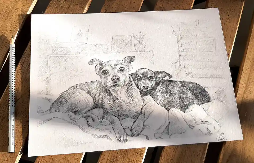 A detailed pencil sketch on paper shows two dogs resting together on a blanket, with a brick wall and potted plant in the…