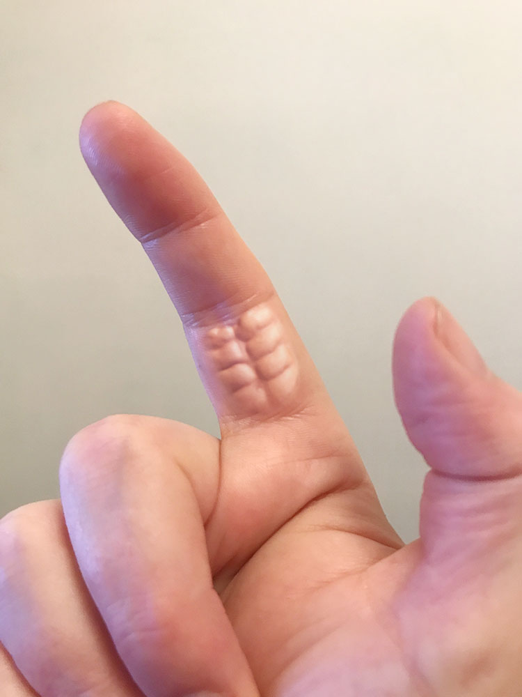 A close-up photo of a person's finger, where the creases and natural skin texture on the side of the finger resemble the…
